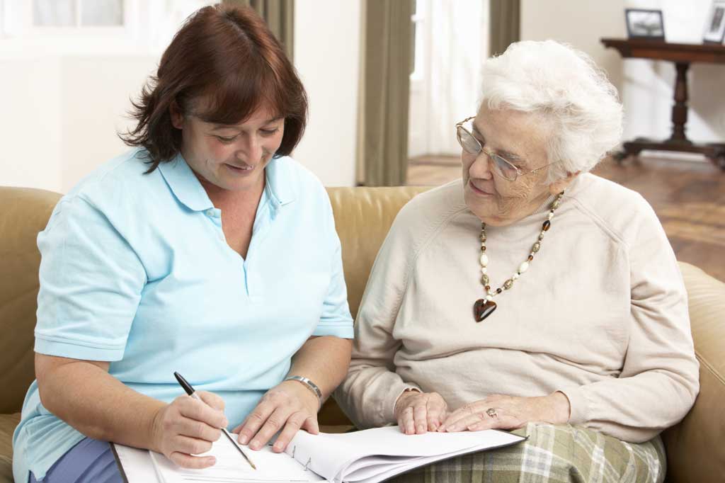 Senior Woman In Discussion With Health Visitor At Home